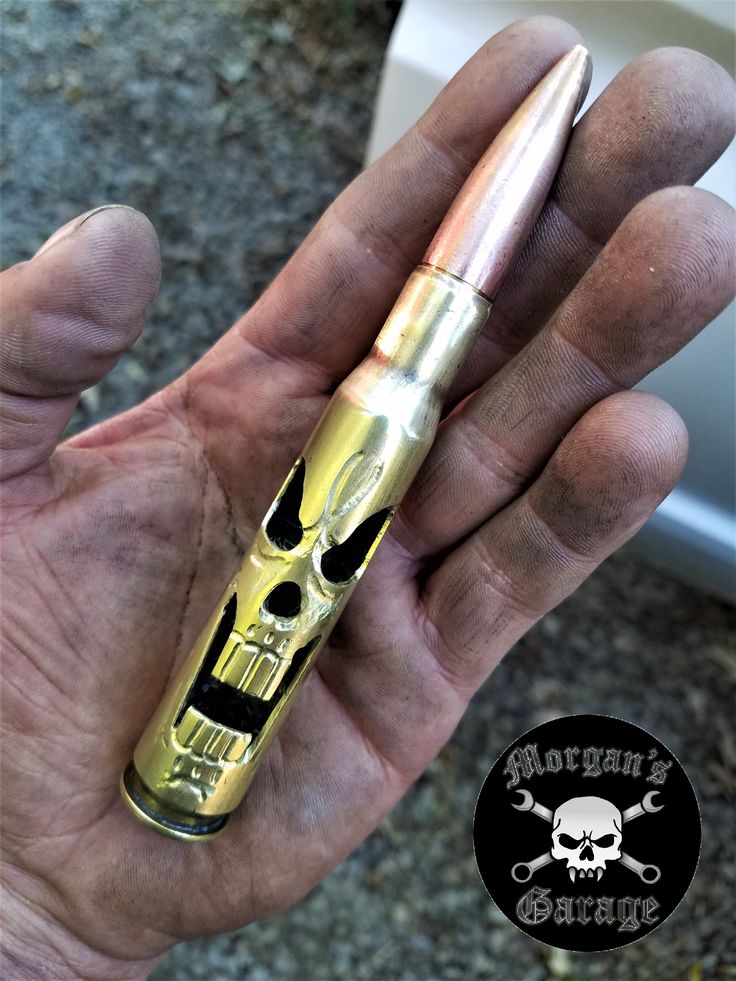 a hand holding a gold colored pen in it's left hand with a skull on it