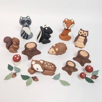 a group of small toy animals sitting next to each other on a white surface with leaves and berries