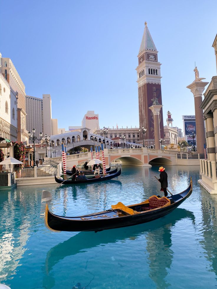 two gondolas in the middle of a canal with buildings and people on it