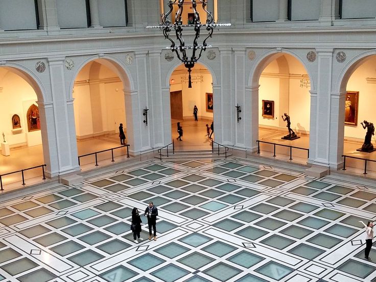 an empty room with chandelier and tiled floor in the center, surrounded by arches