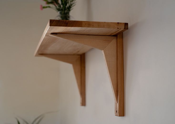 a wooden shelf mounted to the side of a wall next to a potted plant