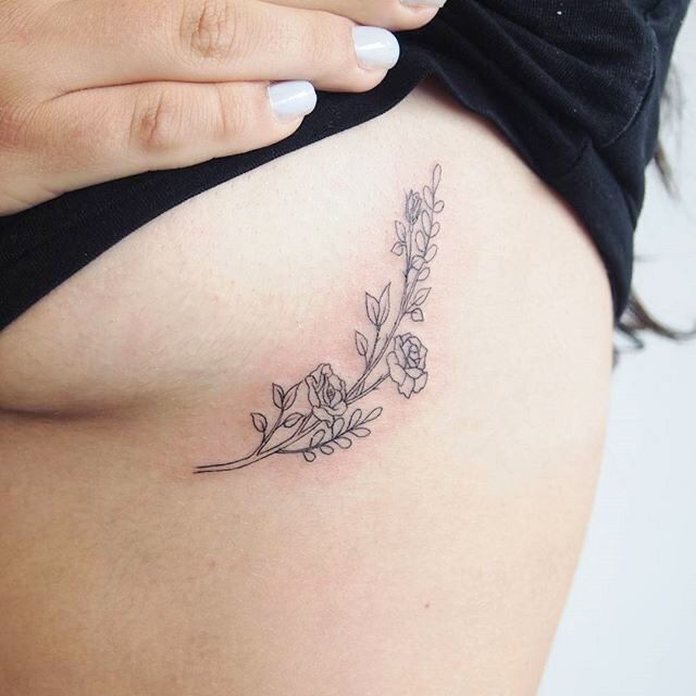 a woman's stomach with a flower tattoo on the side of her belly,