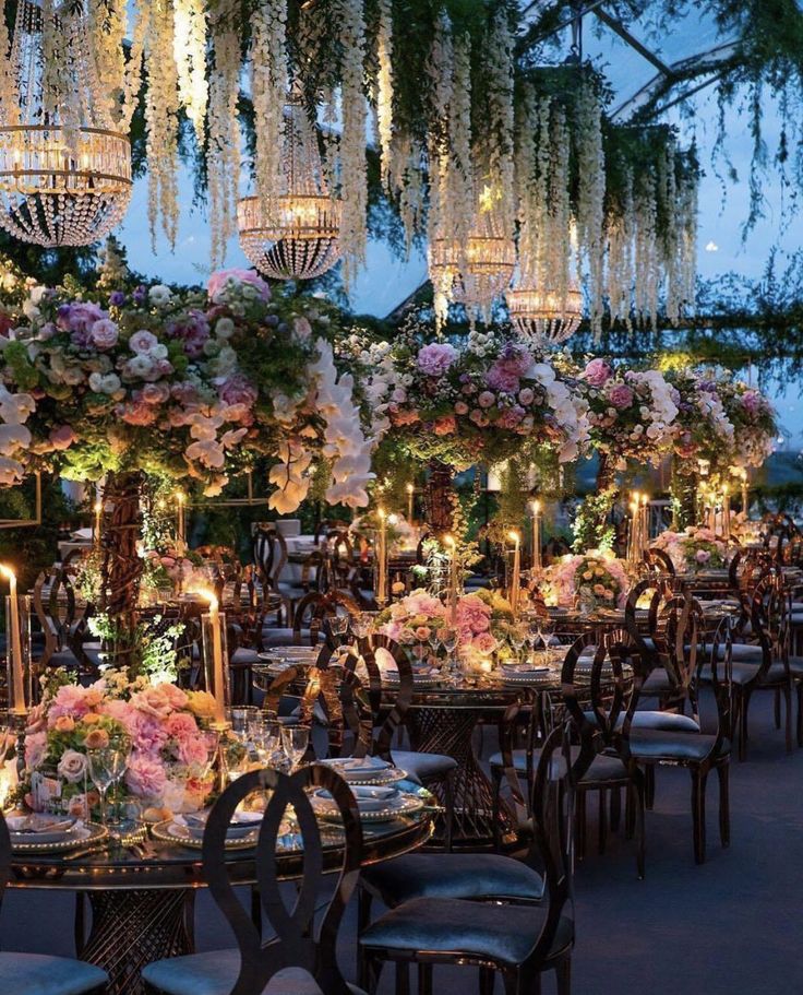 an outdoor dining area with chandeliers and flowers