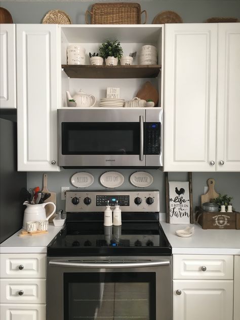 a kitchen with white cabinets and stainless steel stove top oven in the corner, open shelves above