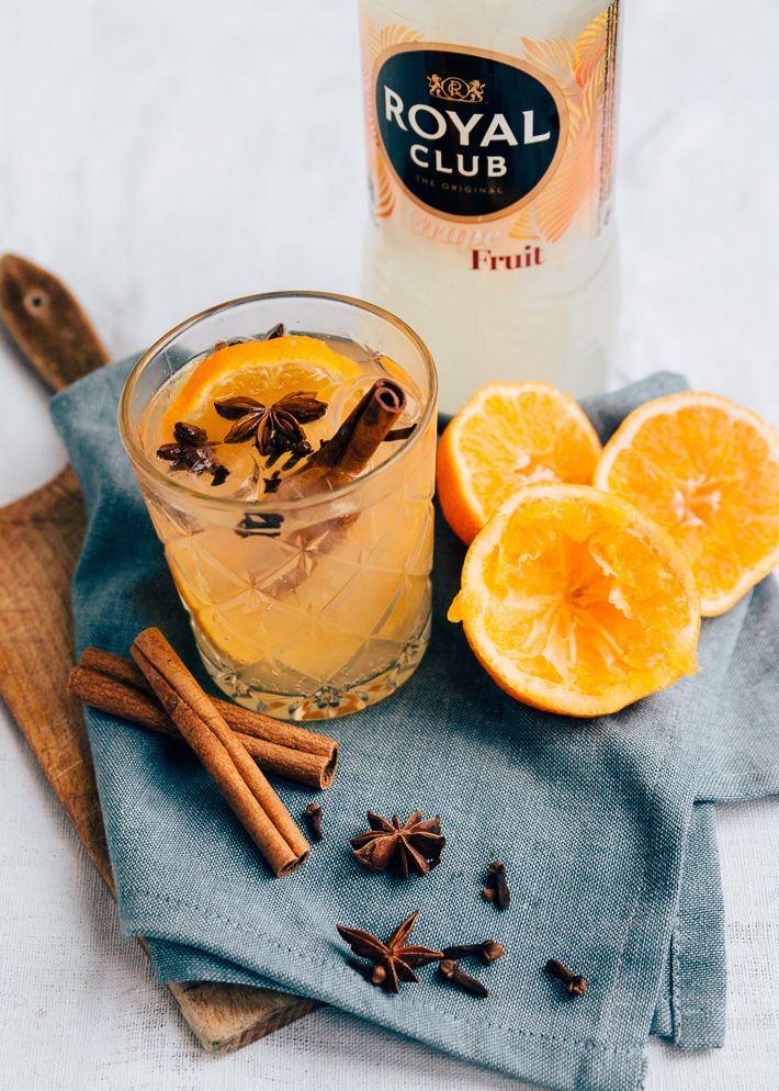 an orange drink with cinnamon and star anise next to it on a blue towel