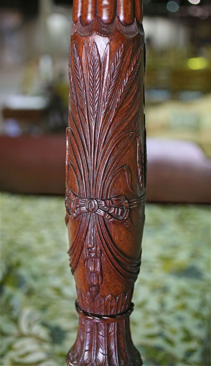 a tall wooden vase with intricate carvings on it's sides sitting on a table