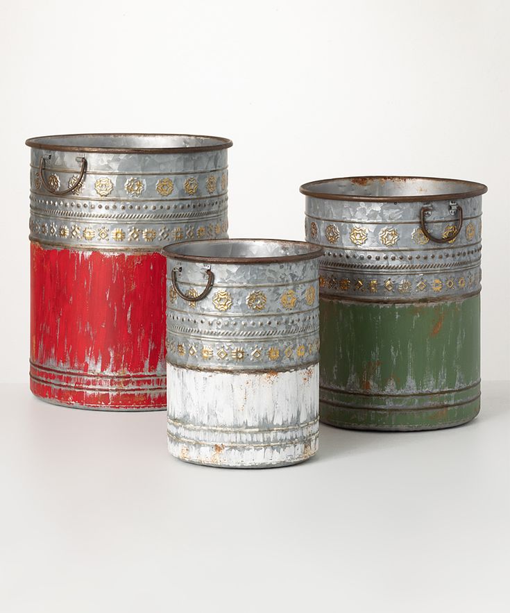 three tin canisters sitting next to each other on a white surface with no one in them