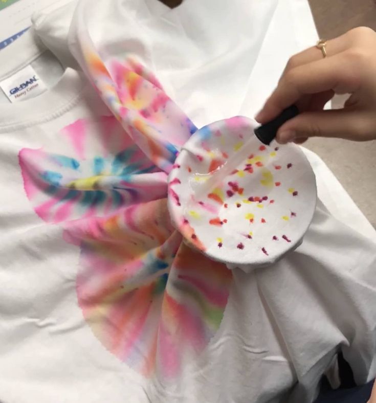 a person is holding a paper plate with sprinkles on it while wearing a white t - shirt