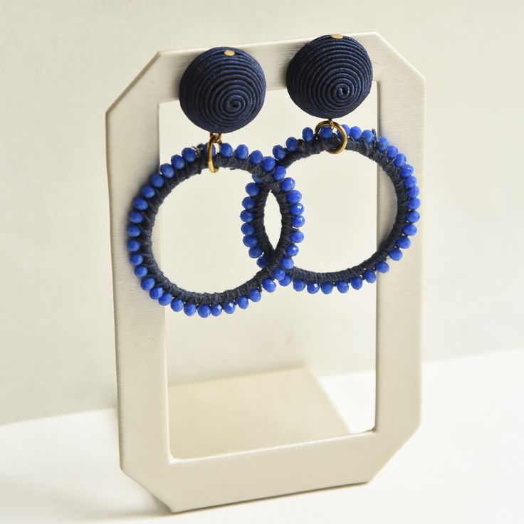 Blue Beaded Loop Earrings - Goldmakers Fine Jewelry Blue Handwoven Beaded Earrings For Gift, Elegant Woven Drop Earrings, Handwoven Blue Beaded Earrings For Gift, Handwoven Blue Jewelry With Round Beads, Blue Handwoven Round Beads Jewelry, Blue Handwoven Round Bead Jewelry, Blue Handwoven Dangle Jewelry, Blue Beaded Clip-on Earrings Gift, Adjustable Blue Earrings With Large Beads