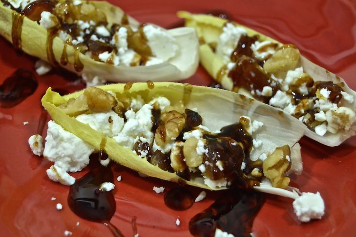 two banana halves with nuts and feta cheese on them sitting on a red plate