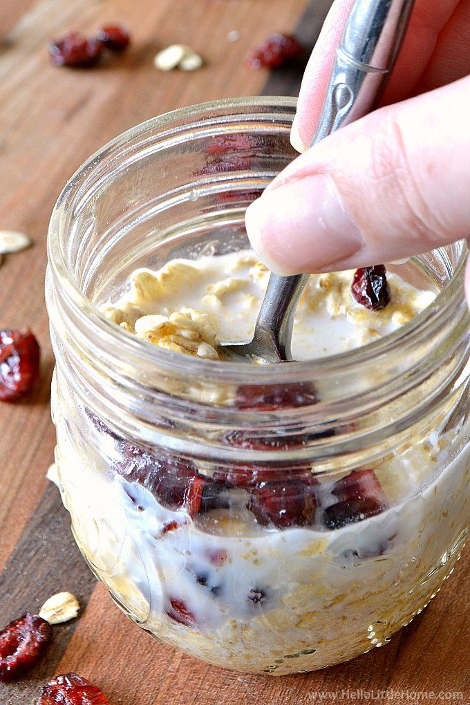 someone is spooning some food into a jar with oatmeal and cranberries