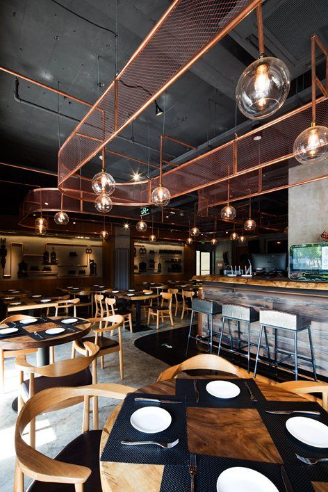 an empty restaurant with wooden tables and chairs, lights hanging from the ceiling over them