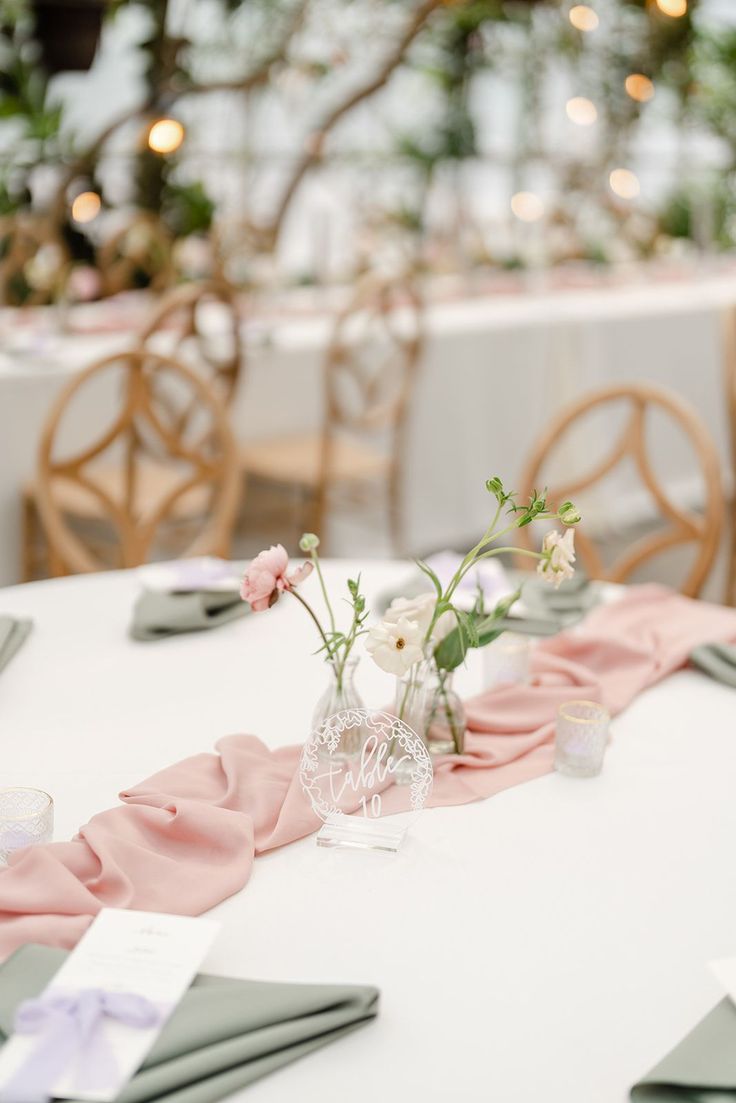 the table is set with napkins and flowers in vases on top of it