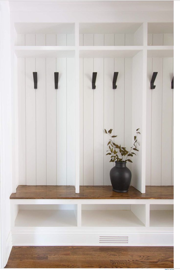 a black vase sitting on top of a wooden shelf next to two white bookshelves