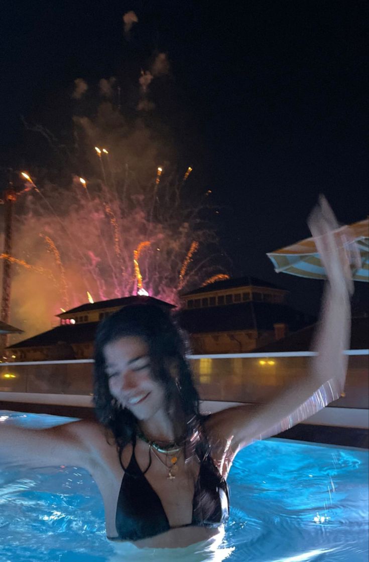 a woman in a swimming pool with fireworks behind her and the caption that reads enviar mensaje