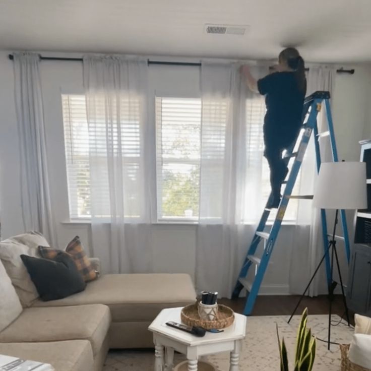 a man standing on a ladder in a living room