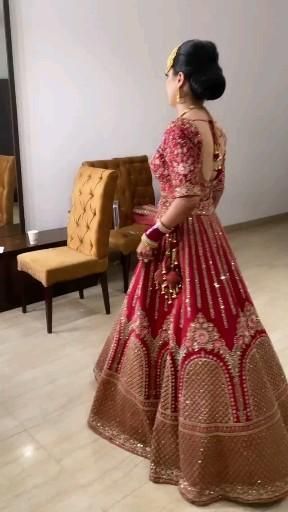 a woman in a red and gold wedding dress looking at herself in the mirror with her hand on her hip