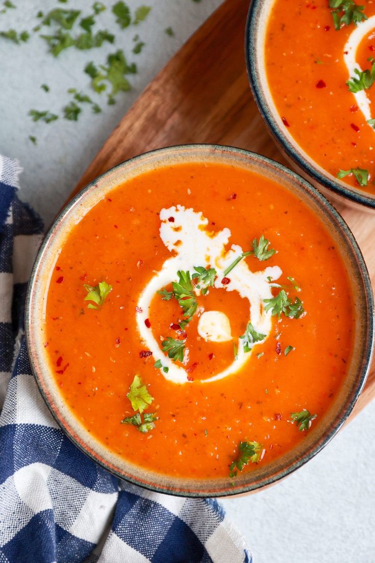 two bowls of tomato soup with parsley on top