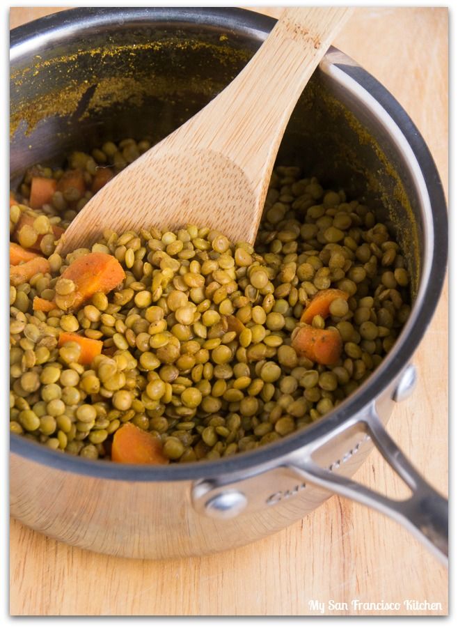 a wooden spoon in a pot filled with green beans and carrots