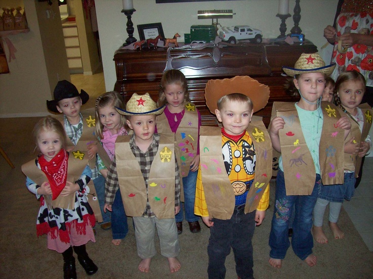 a group of young children wearing costumes and holding up cardboard boxes with cowboy hats on them