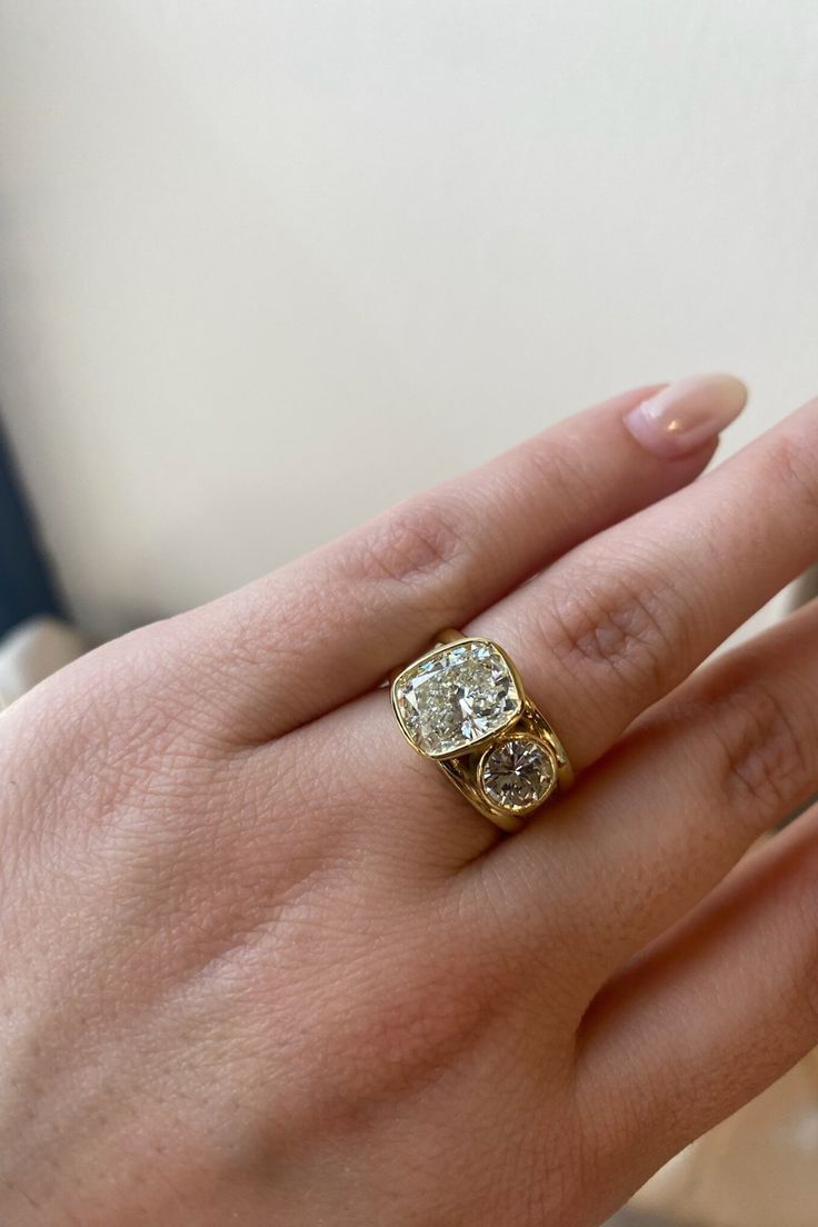 a woman's hand with a yellow and white diamond ring on top of it