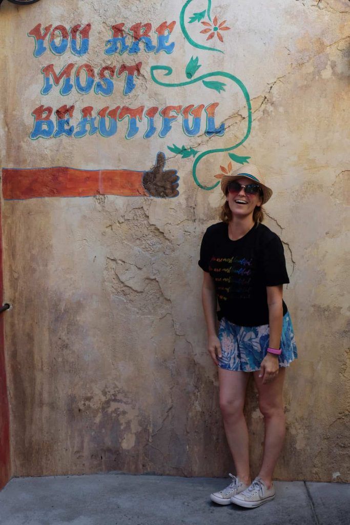 a woman standing in front of a sign that says you are most beautiful