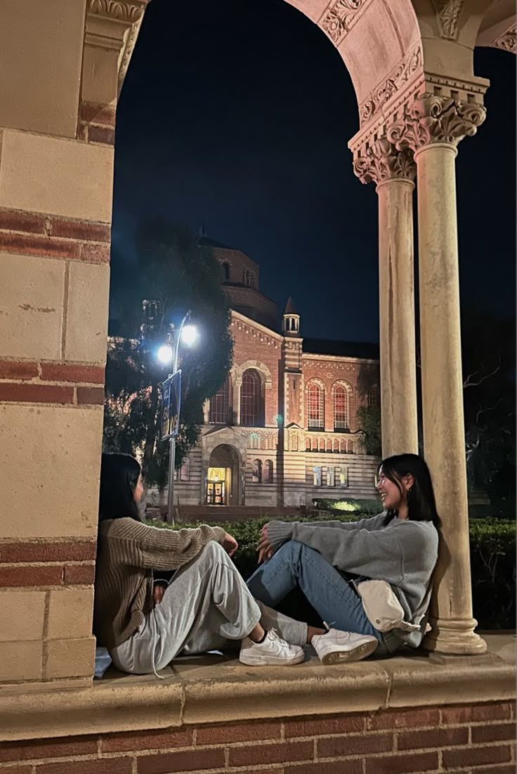 two people sitting on a ledge at night