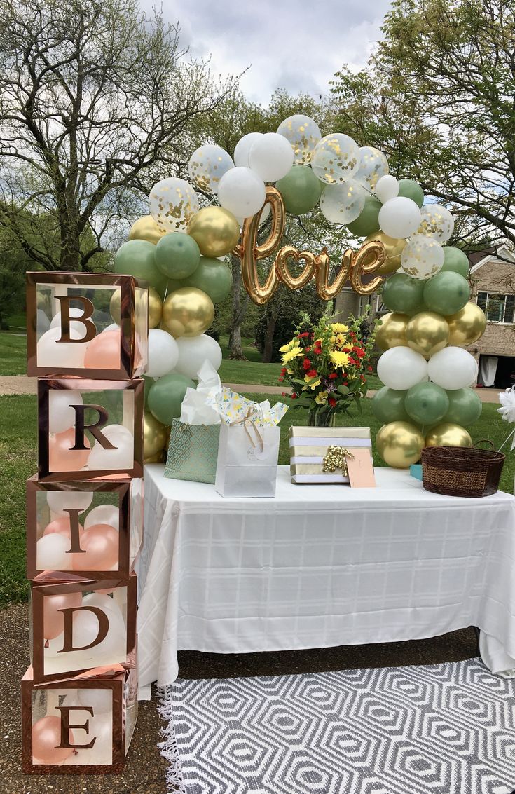 a table topped with balloons and letters next to a sign that says'bride '