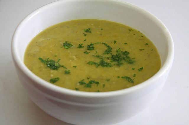 a white bowl filled with soup and garnished with parsley on the side