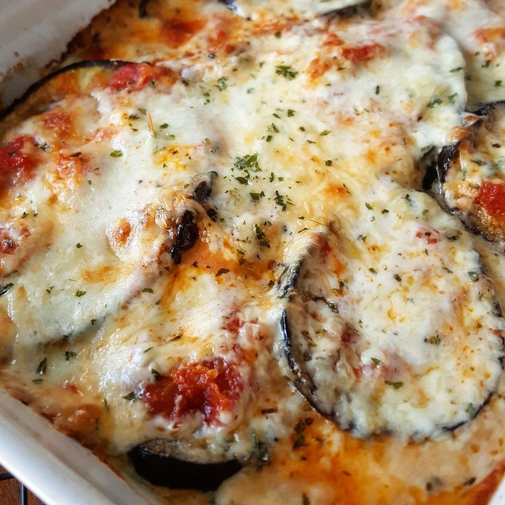 a casserole dish with cheese, mushrooms and sauce in it on a wooden table