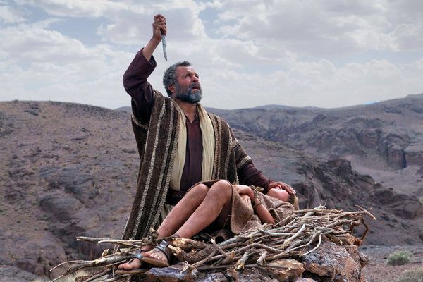 a man sitting on top of a pile of branches in the middle of a desert