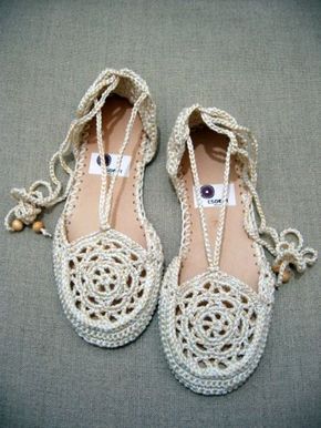 white crocheted shoes with beads on the toes and heel are sitting on a gray surface