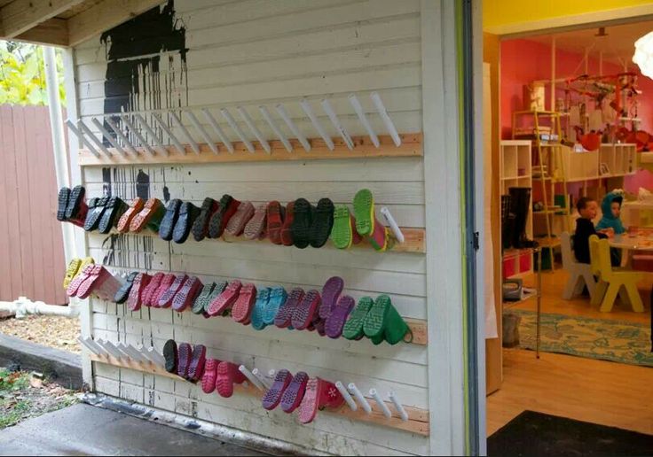 there are many pairs of shoes hanging on the wall in front of this storefront