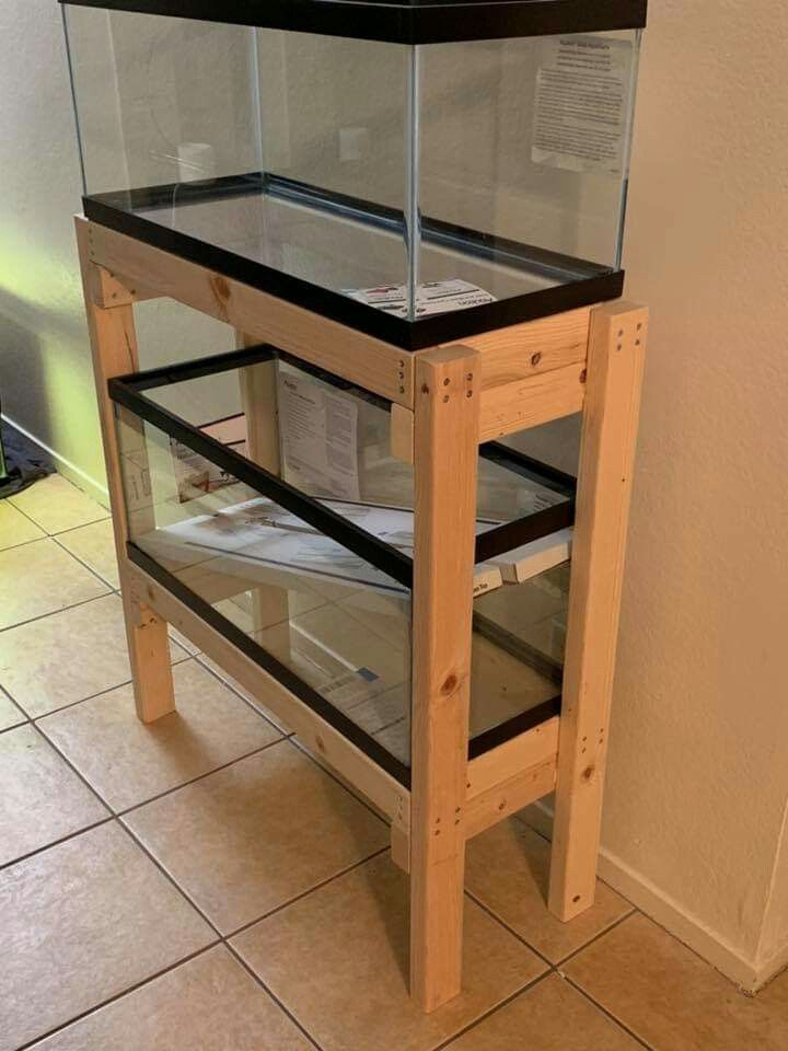 a fish tank sitting on top of a wooden shelf next to a tiled floor and wall