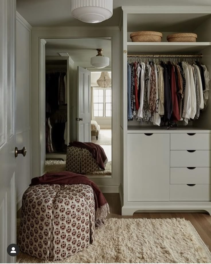 a closet with clothes hanging on the wall and a footstool in front of it