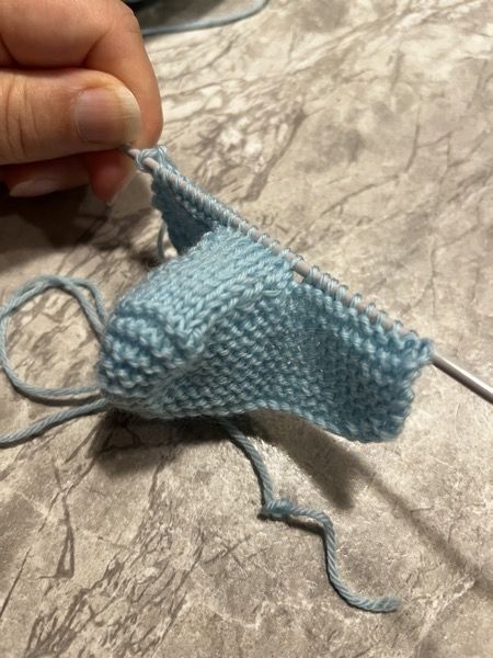 someone is knitting something blue on the table