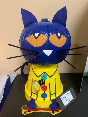 a blue and yellow paper mache cat sitting on top of a table