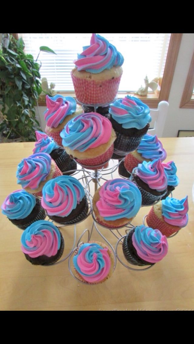 cupcakes with blue and pink frosting are arranged on a wire stand