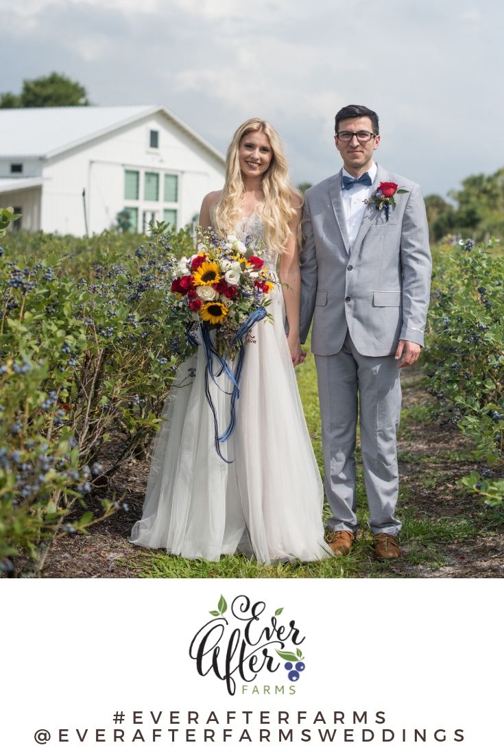 a man and woman standing next to each other in front of some bushes with flowers