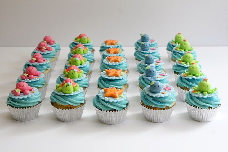 cupcakes with blue frosting and sea creatures on them are arranged in rows