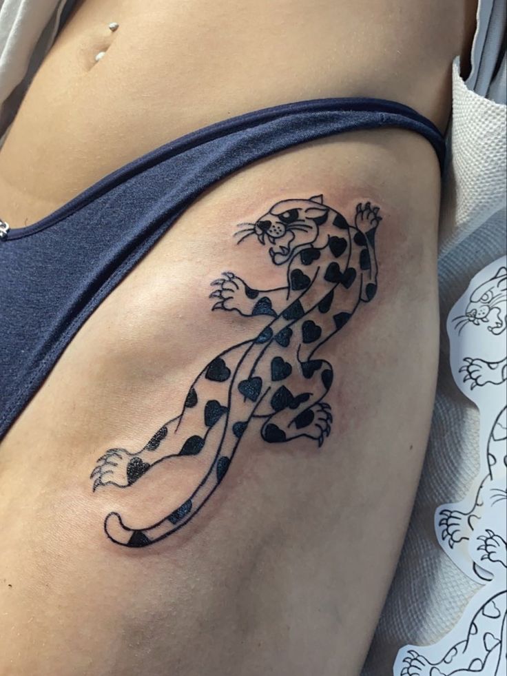 a tattoo on the side of a woman's stomach that has a black and white leopard