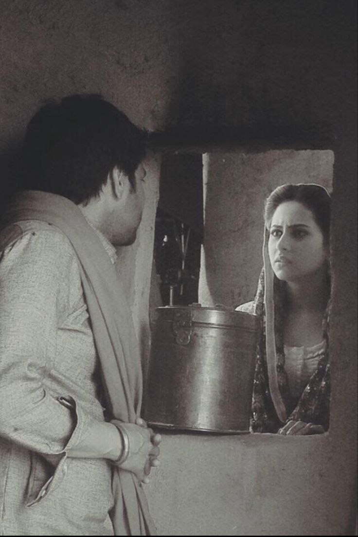 a man and woman standing in front of a mirror looking at each other while holding a pot