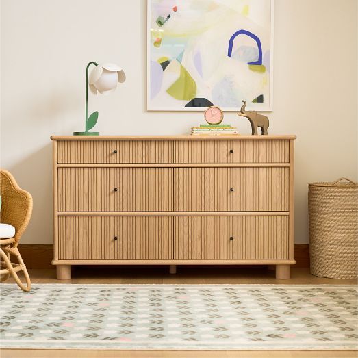 a dresser and chair in a room with a painting on the wall next to it