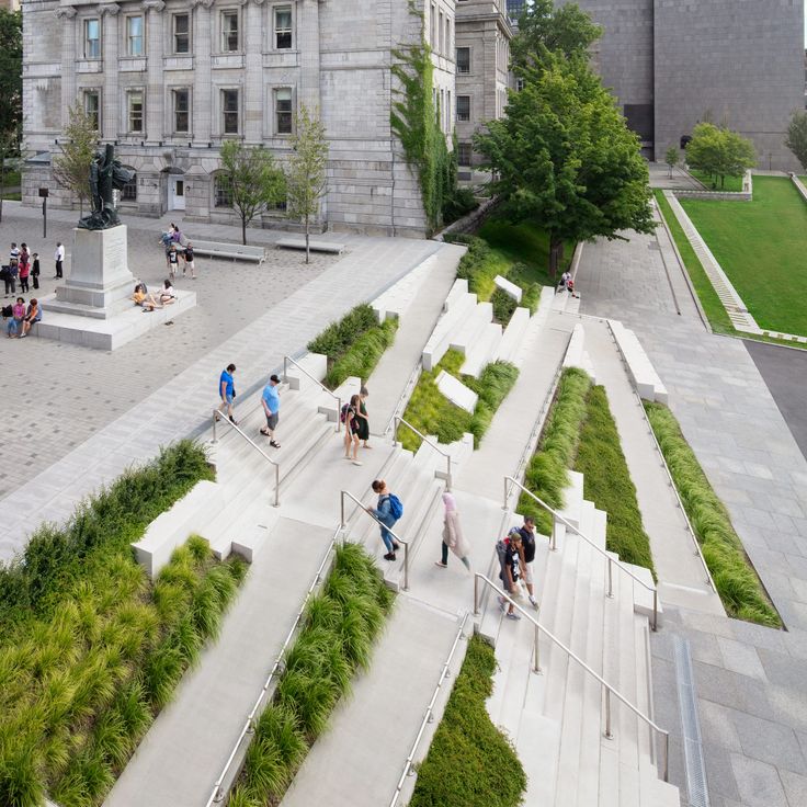 people are walking up and down the stairs in front of a large building with green plants growing on it