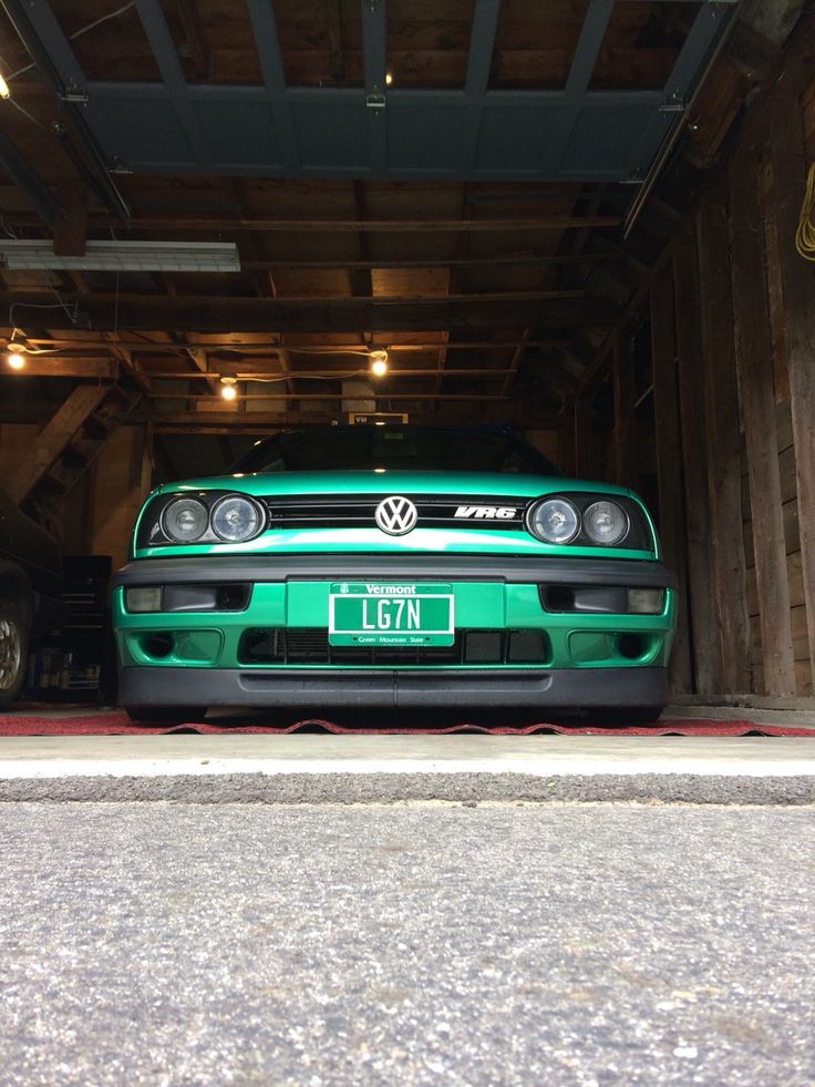 a green car parked in a garage with the license plate vw on it's front