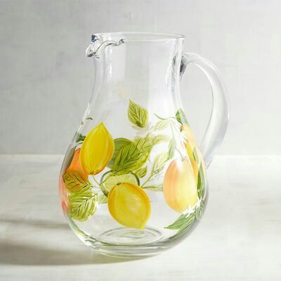 a glass pitcher with lemons and leaves painted on it