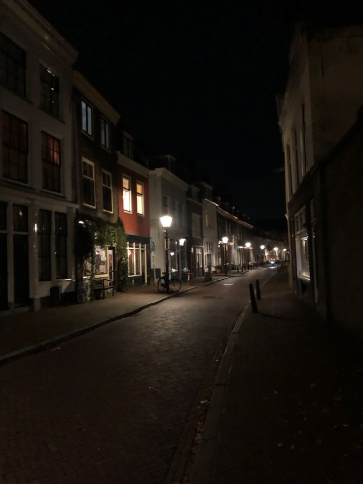 an empty city street at night with no one on the sidewalks or people walking down it