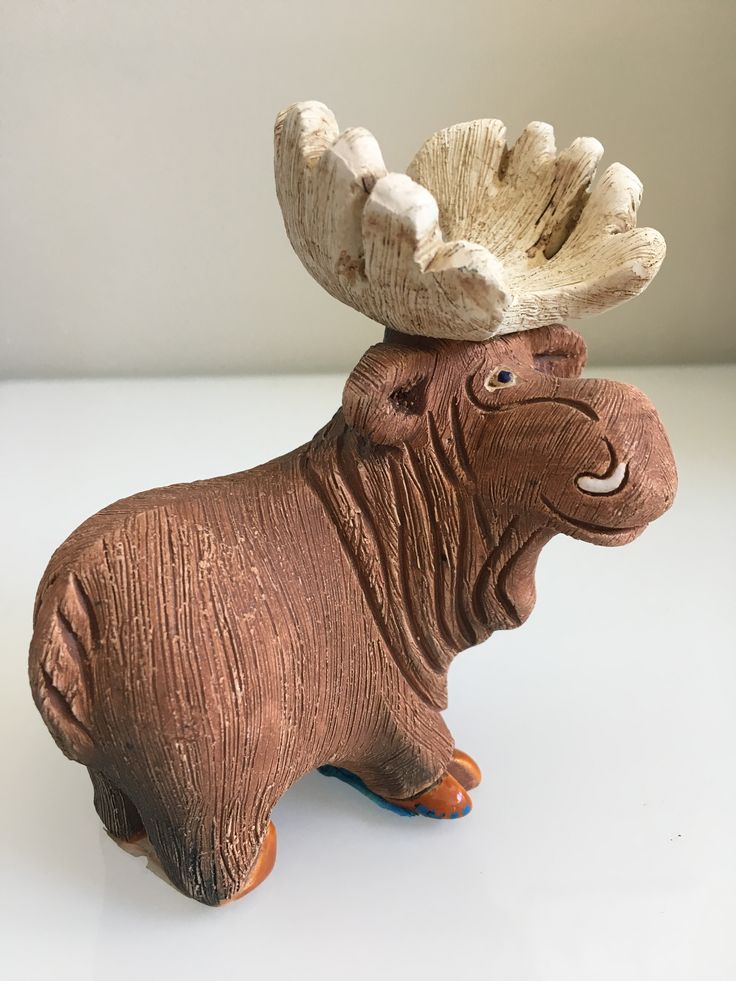 a ceramic moose with antlers on its head sitting on a white counter top next to a wall