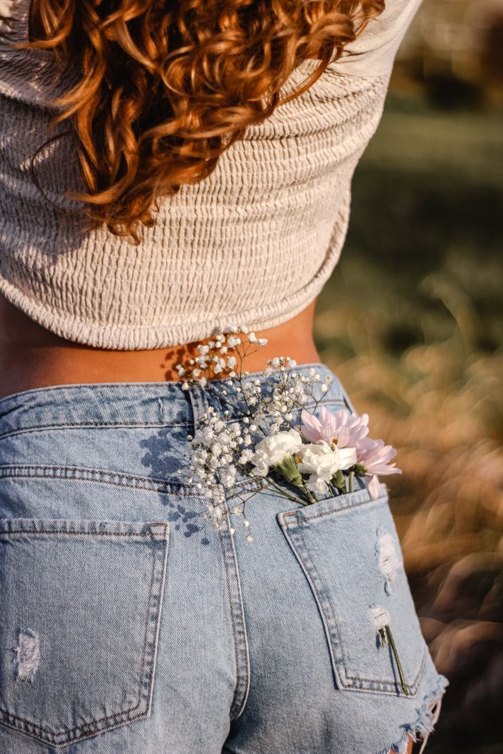 a woman wearing jeans with flowers in her pocket