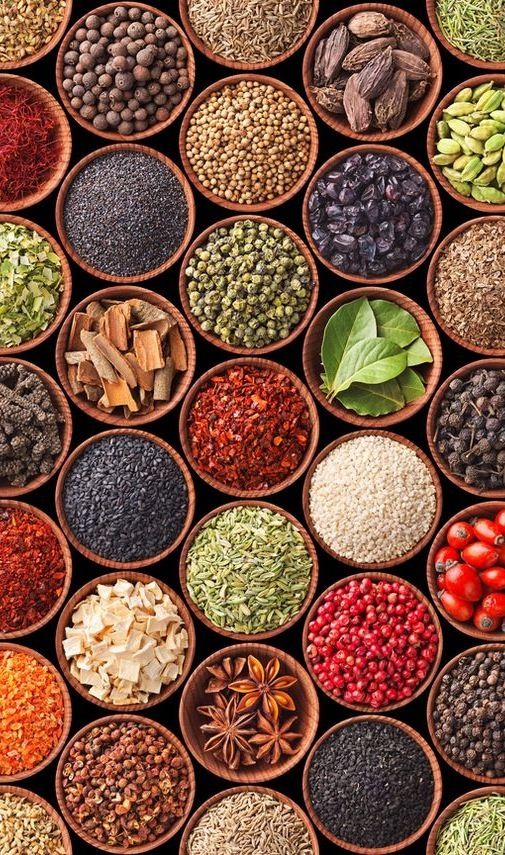 many different types of beans and nuts in wooden bowls on a black background with green leaves